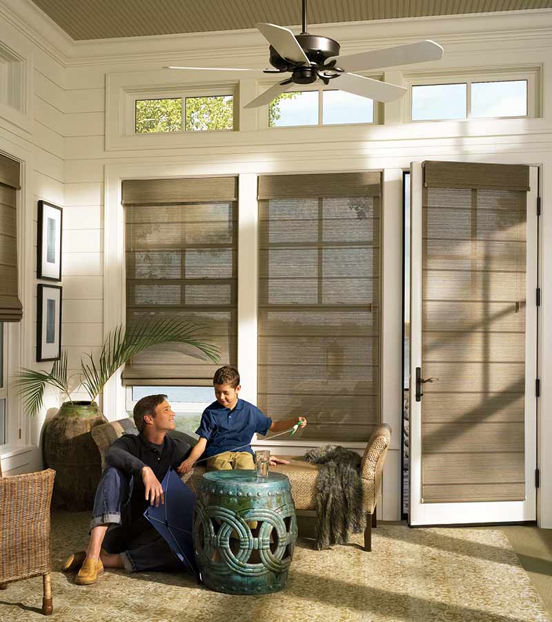 Dad and son in patio sunroom with soft grey roller shades in Overland Park, KS