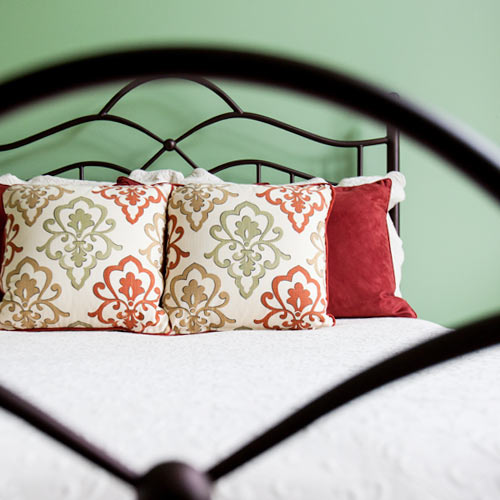 green and red bedding on white bed iron headboard