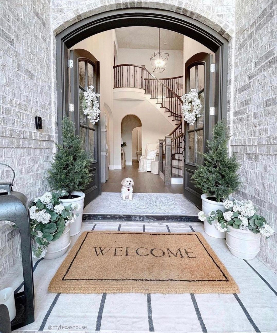 welcome mat outside brick arched entryway of home