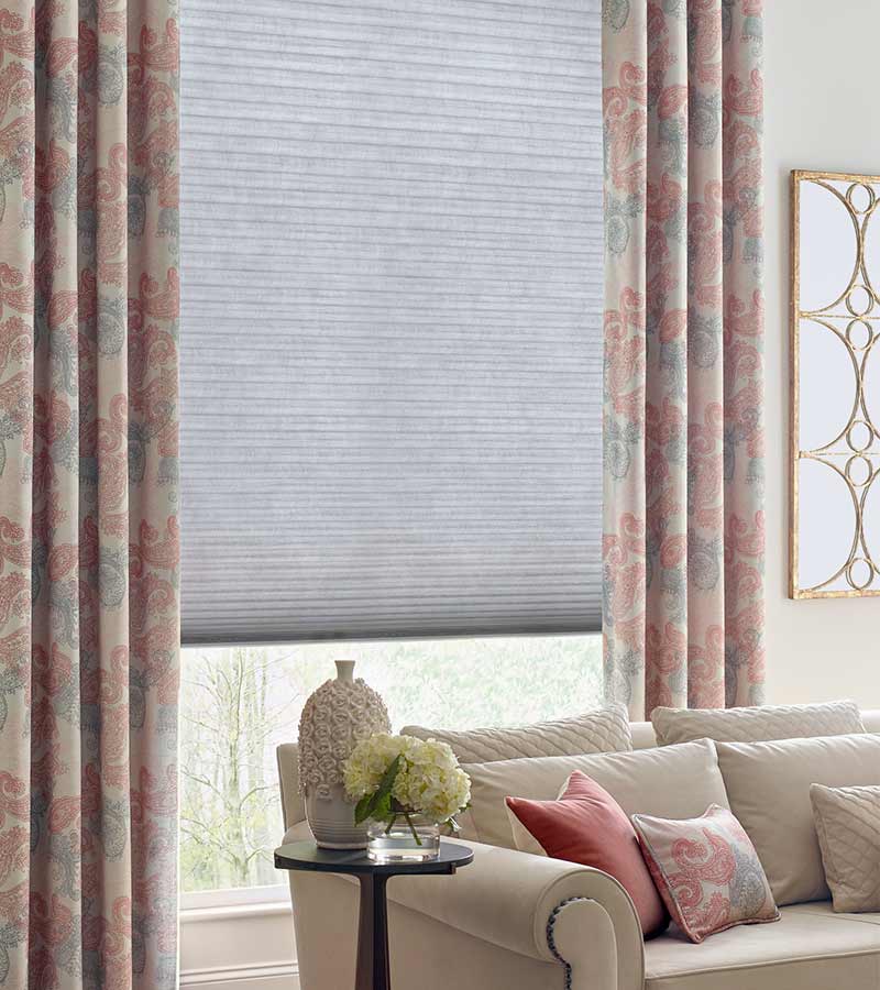 green and pink paisley pattern on drapes next to beige couch