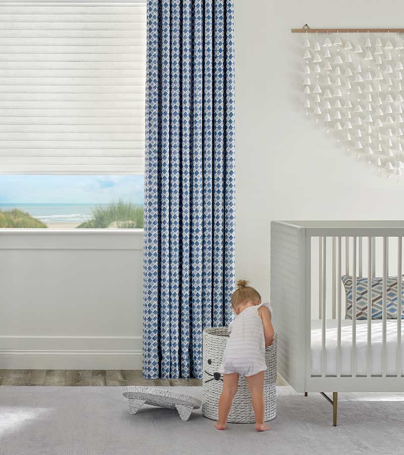 little girl playing in nursery with blue patterned drapery overlooking lake in Lee's Summit, MO