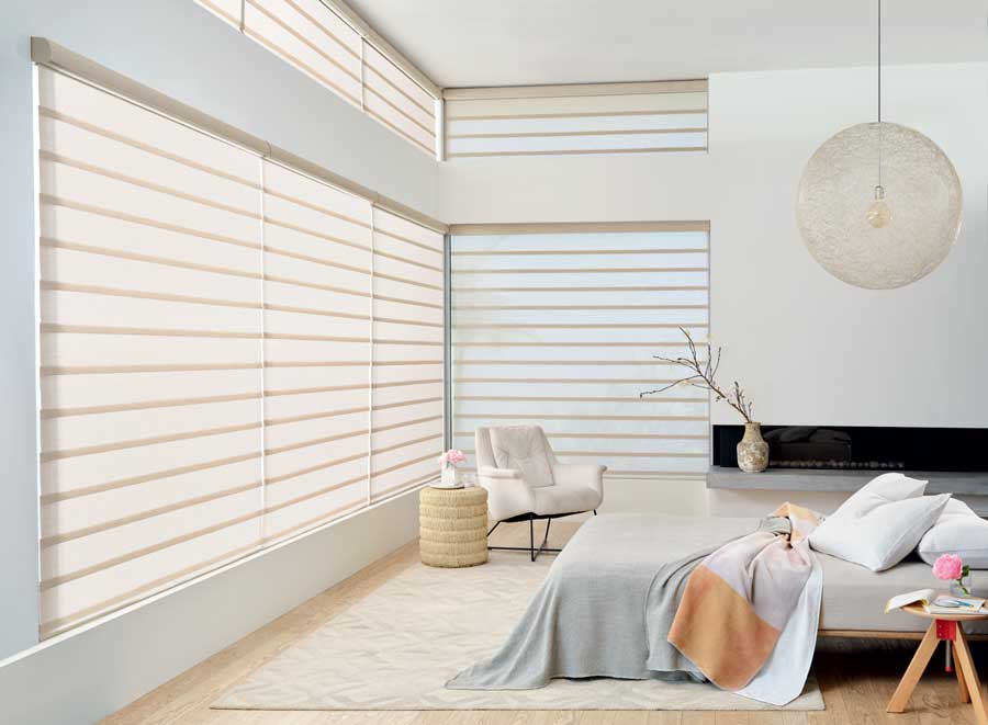 Roller roman shades in a white bedroom.